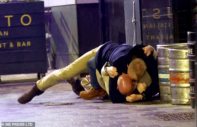 Zwei Männer sind in einen Kampf verwickelt, während sie auf dem Boden der Innenstadt von Leeds raufen