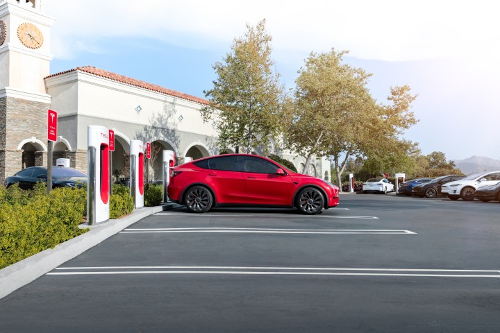 Ein roter Tesla lädt an einer Reihe von Tesla-Superchargern.