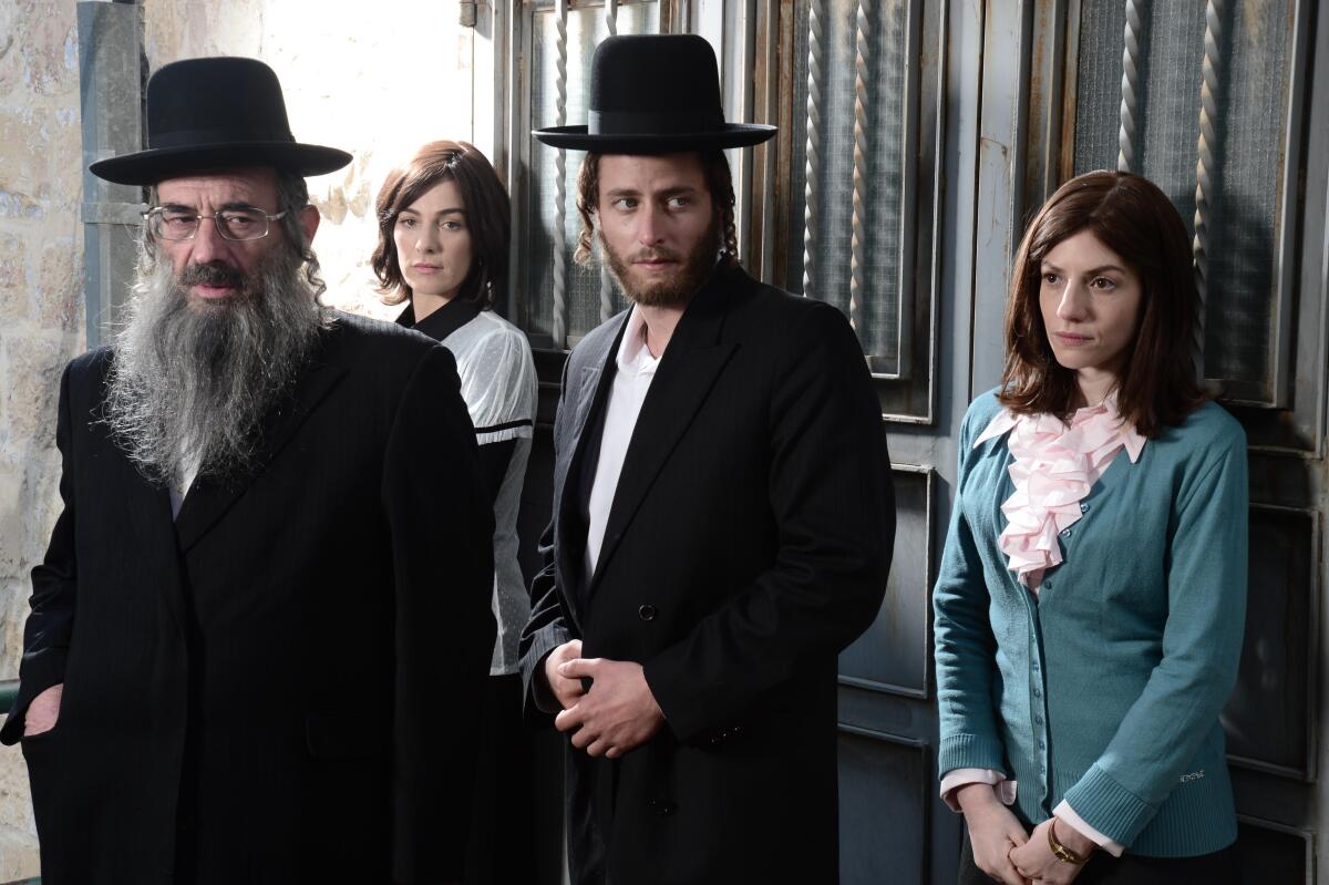 Vier orthodoxe Juden, zwei Männer und zwei Frauen, stehen in einer Tür.