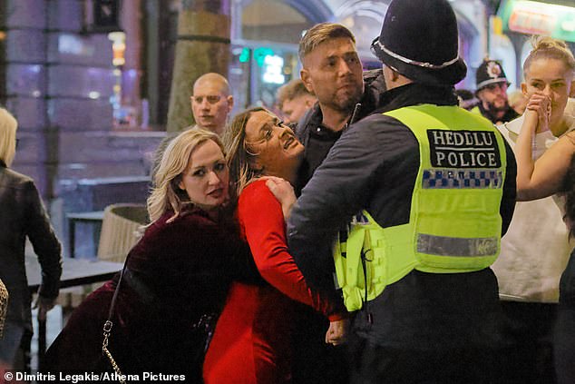 The third photo displays a man and woman arguing with a police officer on the hectic street, whilst another woman lovingly hugs the pair of them