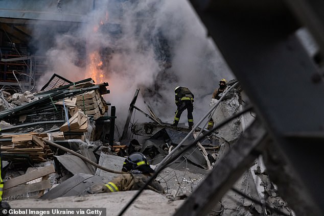 Feuerwehrleute löschen am 29. Dezember 2023 nach einem russischen Raketenangriff in Charkiw, Ukraine, einen Brand in einem beschädigten Unternehmen
