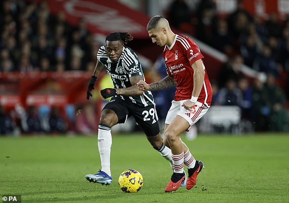 Manchester United's Aaron Wan-Bissaka (left) and Nottingham Forest's Nicolas Dominguez battle for the ball during the Premier League match at the City Ground, Nottingham. Picture date: Saturday December 30, 2023. PA Photo. See PA story SOCCER Forest. Photo credit should read: Richard Sellers/PA Wire.RESTRICTIONS: EDITORIAL USE ONLY No use with unauthorised audio, video, data, fixture lists, club/league logos or "live" services. Online in-match use limited to 120 images, no video emulation. No use in betting, games or single club/league/player publications.