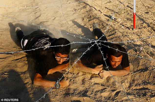 Junge palästinensische Männer kriechen während einer Militärübung in einem vom bewaffneten Flügel der Hamas organisierten Sommerlager unter einem Hindernis hindurch