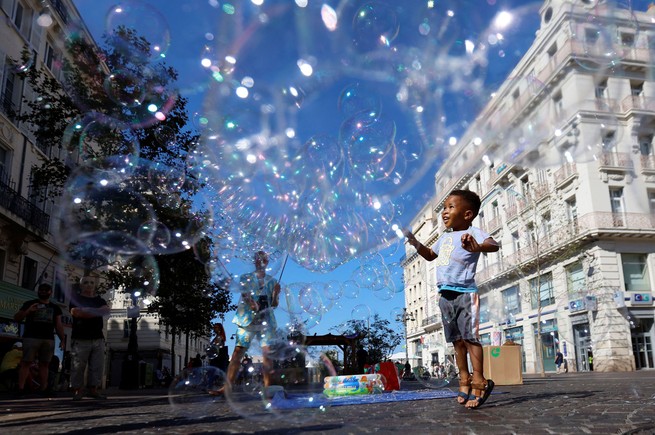Ein Kind spielt mit Seifenblasen eines Straßenkünstlers am Alten Hafen in Marseille, Frankreich