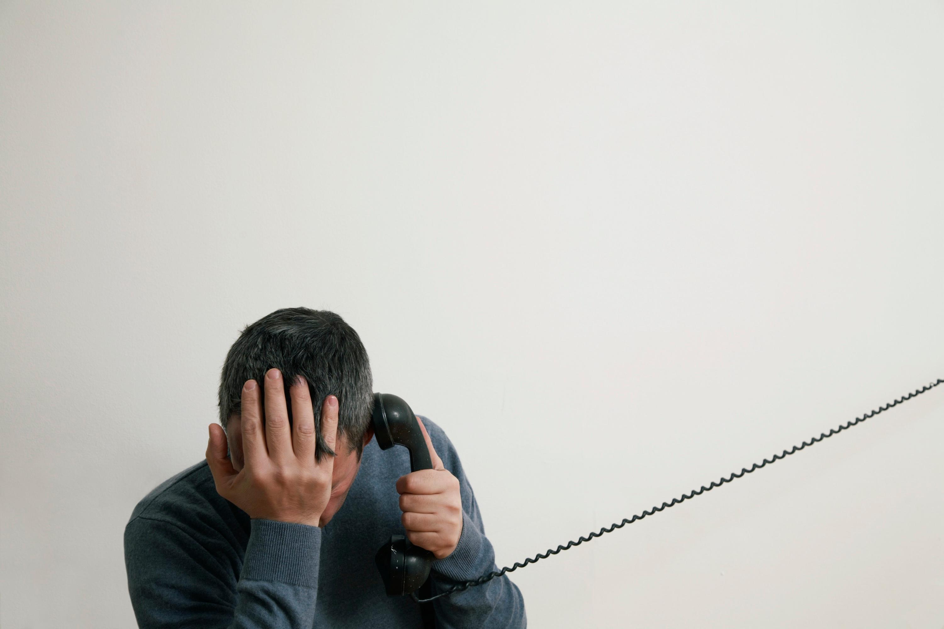 Mann sitzt auf der Treppe und telefoniert mit der Hand am Kopf