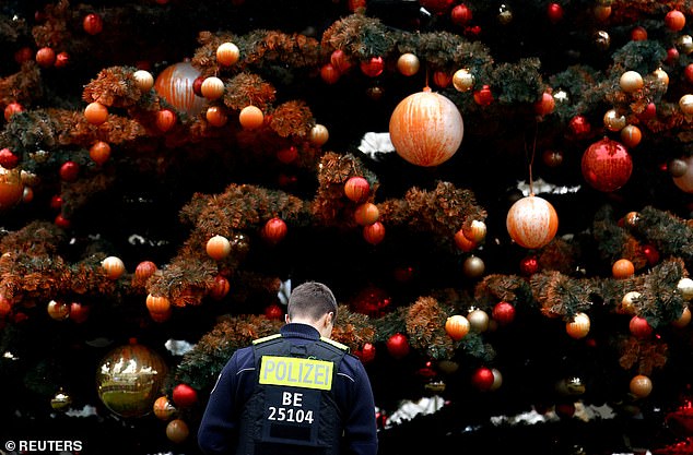 Ein Polizist in Berlin inspiziert einen Weihnachtsbaum, nachdem Klimaaktivisten der Gruppe Letzte Generation, die von einer kalifornischen Klimagruppe finanziert wird, ihn mit orangefarbener Farbe besprüht haben