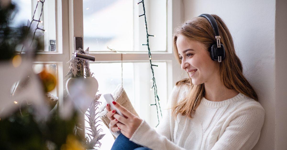 Mädchen trägt Kopfhörer und hört Musik rund um Weihnachtsdekorationen