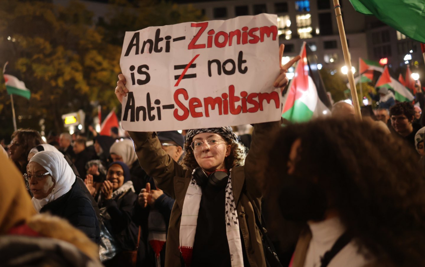 Ein junger Mensch hält während eines Protestmarsches „Freiheit für Palästina“, an dem am 4. November 2023 in Berlin Tausende Teilnehmer teilnahmen, ein Schild mit der Aufschrift „Antizionismus ist kein Antisemitismus“.