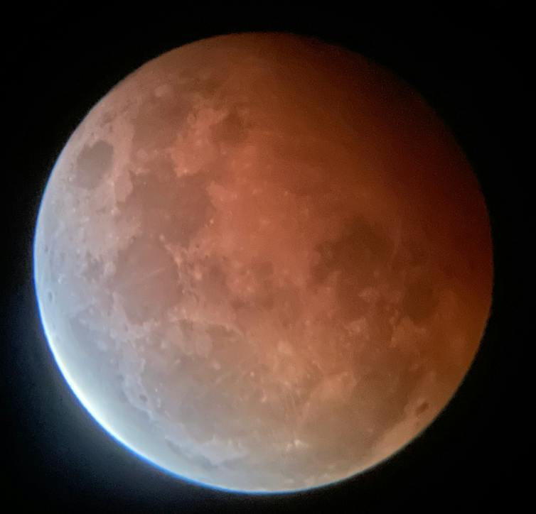 Eine vergrößerte Ansicht des Mondes, auf dessen eine Seite ein roter Schatten fällt