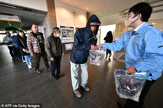 People receive water packs at the Shika Town hall in Shika, Ishikawa prefecture on January 2, 2024, a day after a major 7.5 magnitude earthquake struck the Noto region in Ishikawa prefecture. Japanese rescuers battled against the clock and powerful aftershocks on January 2 to find survivors of a major earthquake that struck on New Year's Day, killing at least six people and leaving a trail of destruction. (Photo by Kazuhiro NOGI / AFP) (Photo by KAZUHIRO NOGI/AFP via Getty Images)