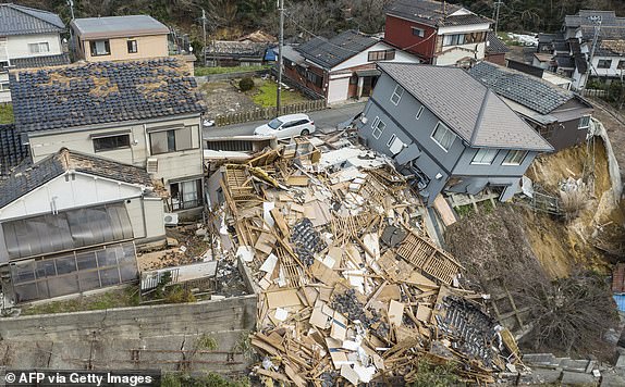 TOPSHOT - This aerial photo shows damaged and destroyed homes along a street in Wajima, Ishikawa prefecture on January 2, 2024, a day after a major 7.5 magnitude earthquake struck the Noto region in Ishikawa prefecture. Japanese rescuers battled against the clock and powerful aftershocks on January 2 to find survivors of a major earthquake that struck on New Year's Day, killing at least six people and leaving a trail of destruction. (Photo by Fred MERY / AFP) (Photo by FRED MERY/AFP via Getty Images)