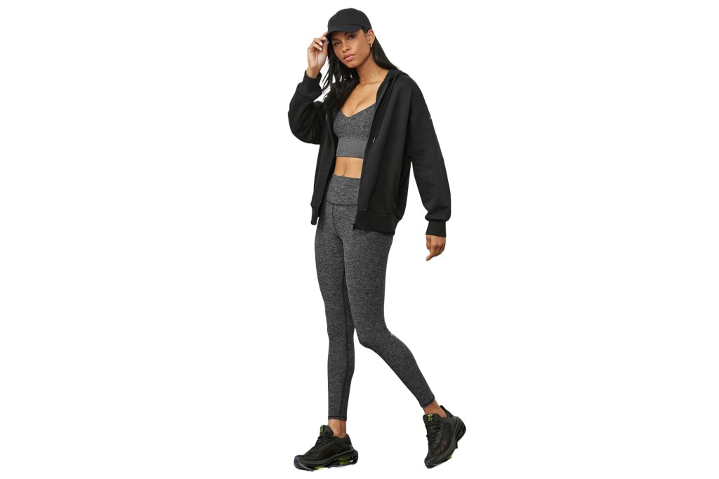 Ein Model in einem passenden grauen Trainingsset sowie einer schwarzen Jacke und Baseballkappe