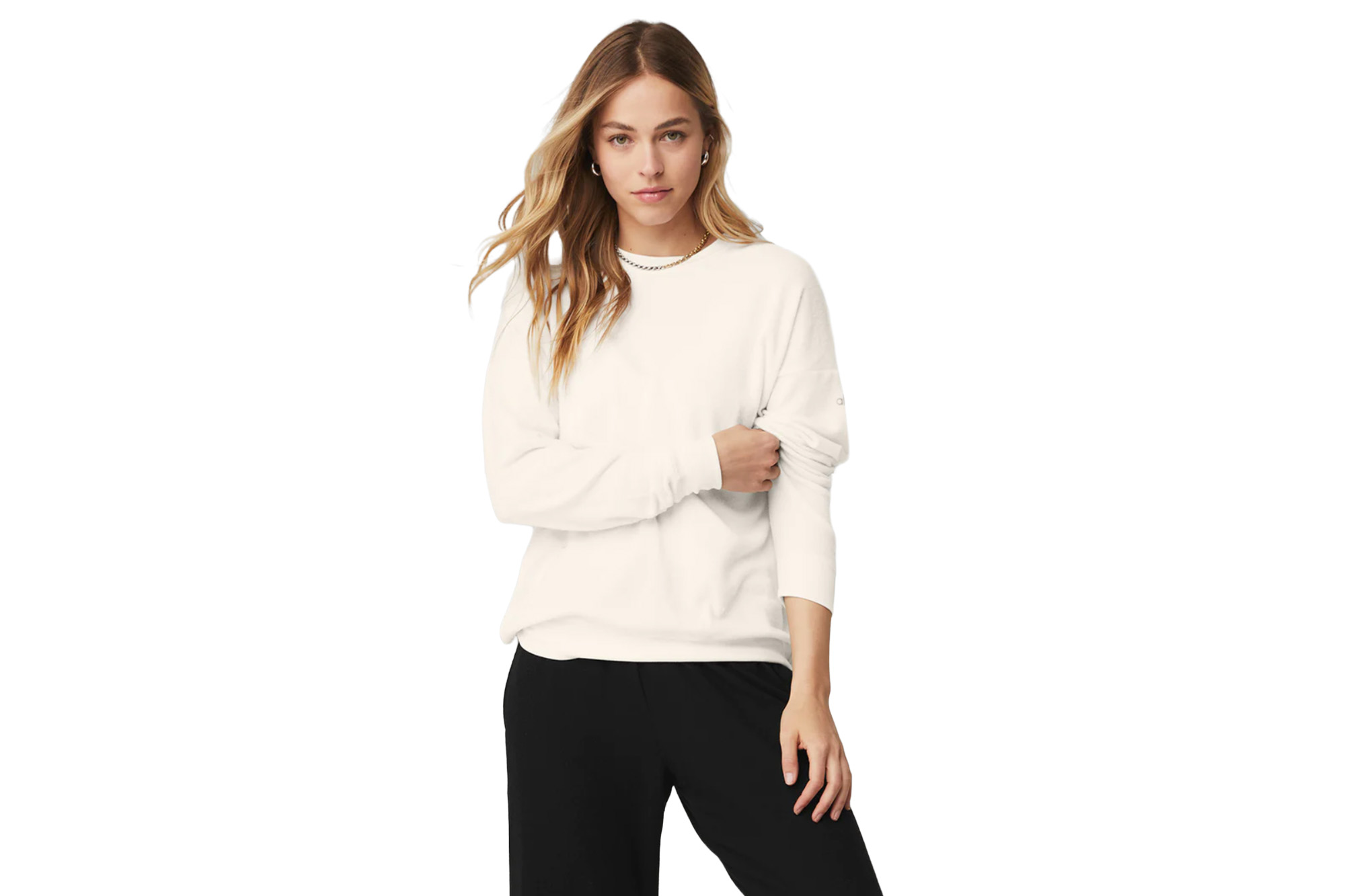 Ein Model in einem cremefarbenen Pullover und schwarzen Jogginghosen