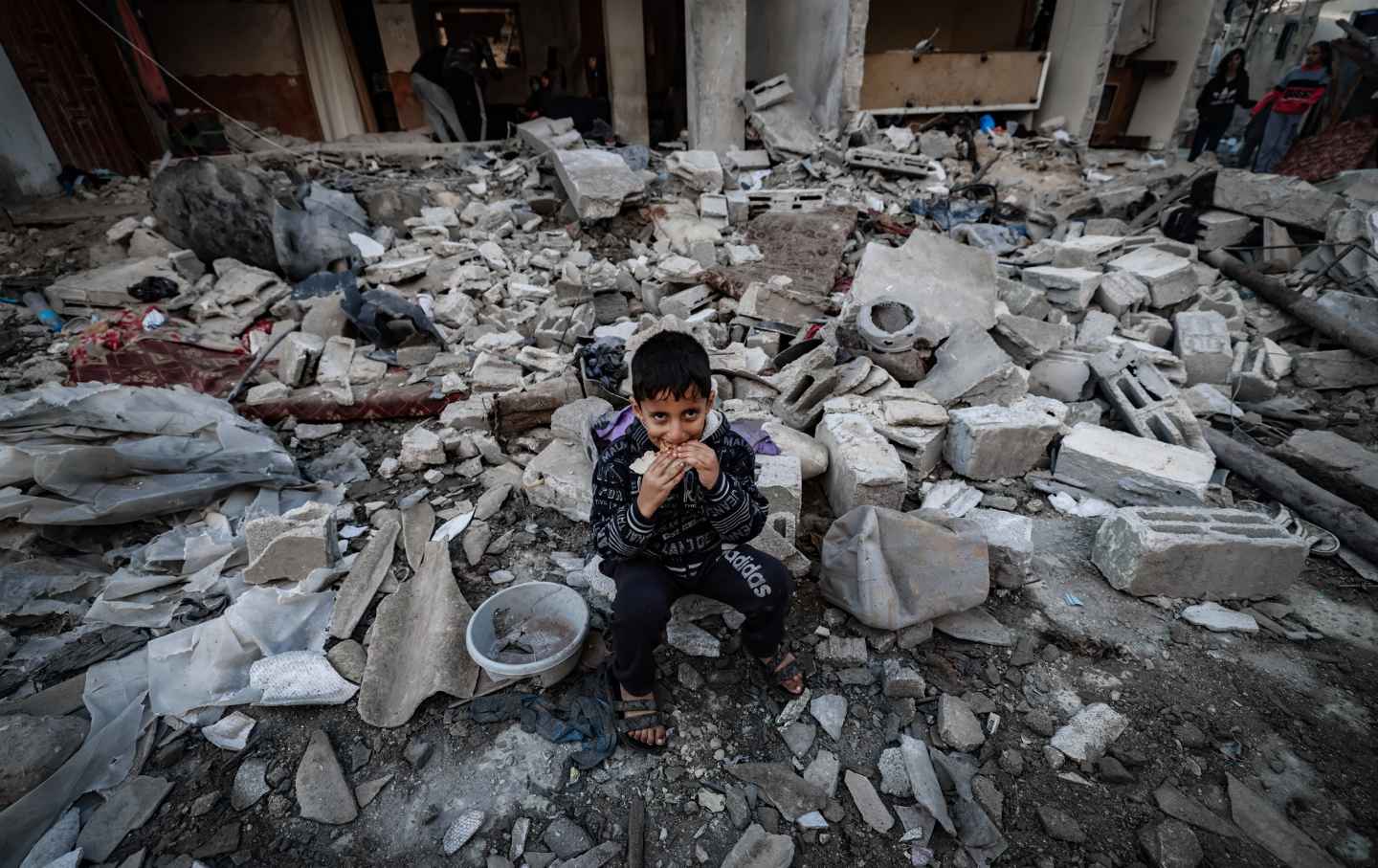 Ein Kind isst inmitten der Trümmer zerstörter Gebäude nach der israelischen Bombardierung in Rafah im südlichen Gazastreifen am 29. Dezember 2023, inmitten der anhaltenden Kämpfe zwischen Israel und der palästinensischen militanten Gruppe Hamas.