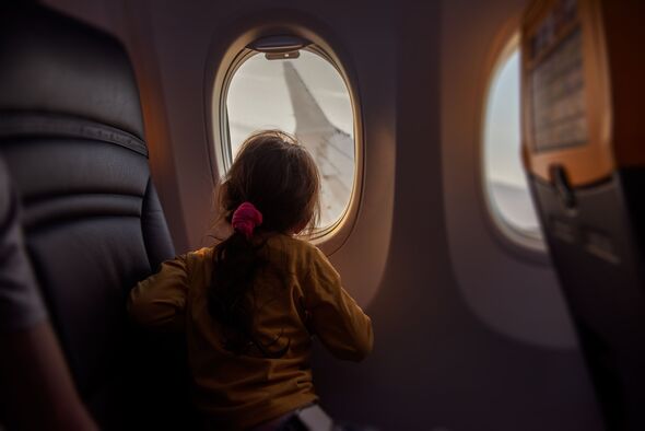 Ein kleines Mädchen schaut aus dem Fenster eines Flugzeugs