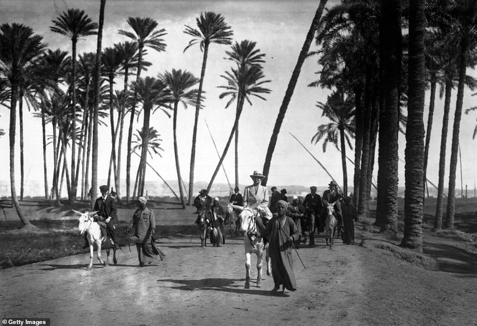 Tourists dressed in their finest attire make their way through date palm groves to the desert in this atmospheric shot taken in Sakkara in March 1921. March is deemed one of the more comfortable months to visit Egypt, with the average high ranging from about 68F to 81F
