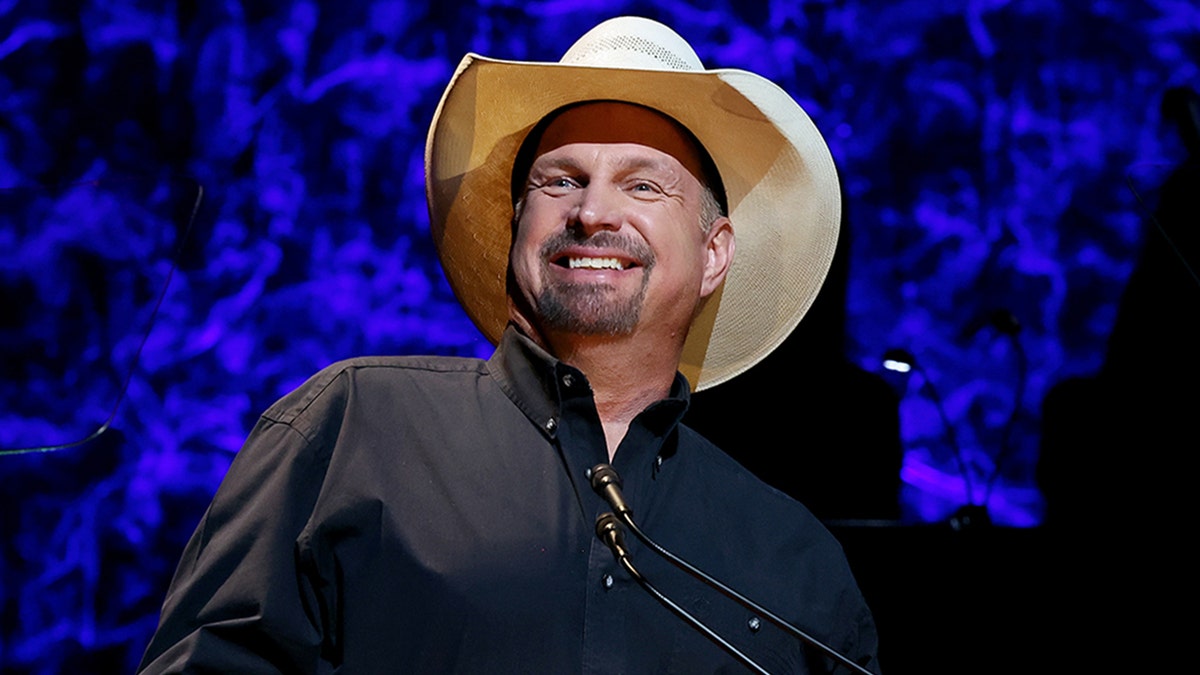 Garth Brooks lächelt in einem braunen Cowboyhut und einem schwarzen Hemd auf der Bühne der County Music Hall of Fame and Museum