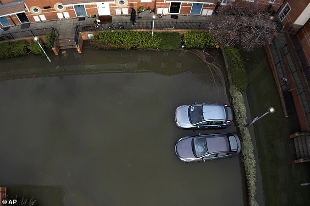 Zwei Autos wurden am Sonntag auf einem überschwemmten Parkplatz in der Nähe der Themse in Oxford zurückgelassen, nachdem eine Woche lang heftige Regenfälle das Land überschwemmt hatten