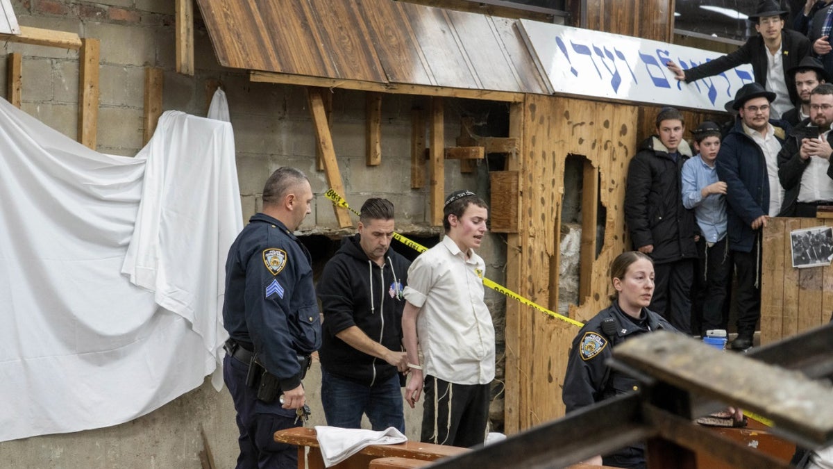 NYPD-Beamte nehmen einen Studenten fest, nachdem er aus einer Bresche in der Wand der Synagoge entfernt wurde, die zu einem von Studenten gegrabenen Tunnel führte.