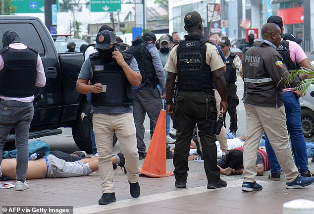 Ecuadorean police officers fuard the arrested suspects outside Ecuador's TC television channel after unidentified gunmen burst into the state-owned television studio live on air on Tuesday
