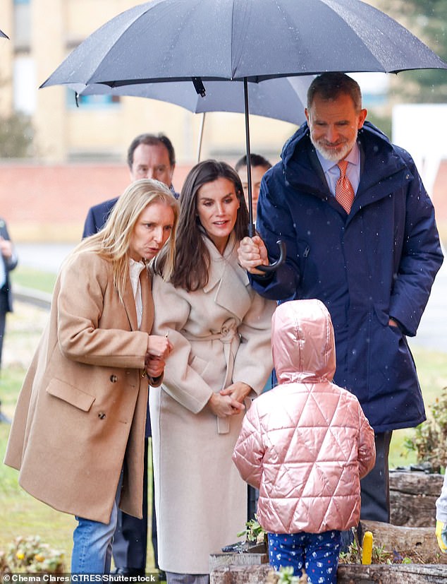 The royal couple sheltered from the rain under an umbrella and they spoke to a young child