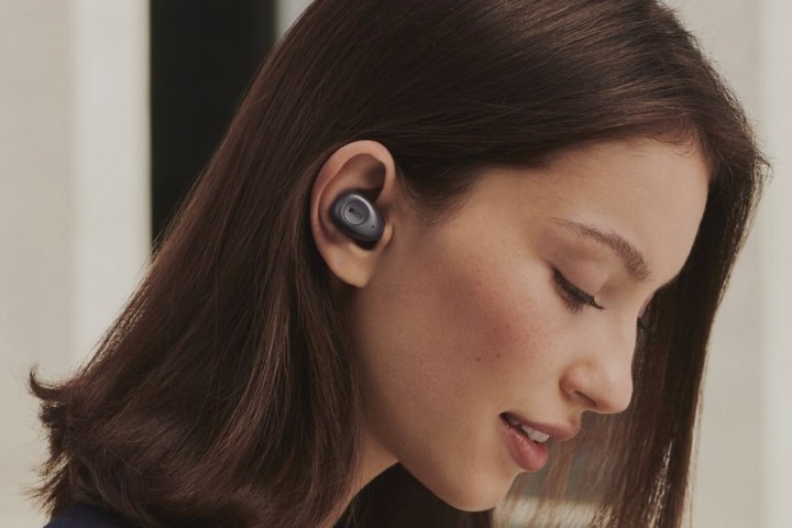 A woman listens to music on KEF Mu3 wireless earbuds.