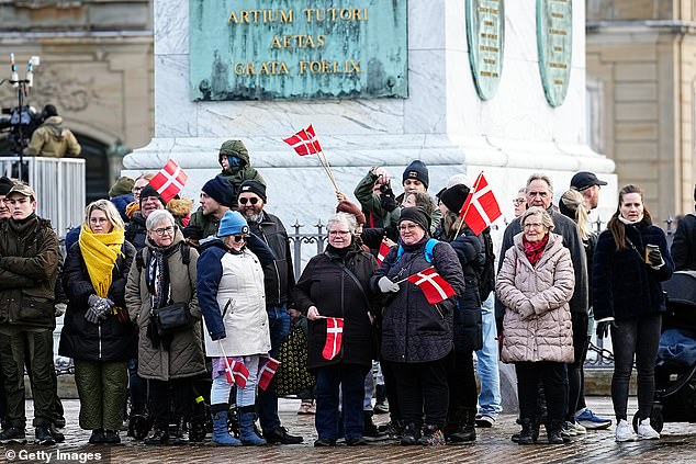 Danish flags are waved as excited crowds gather round the Amalienborg Palace Square in Copenhagen
