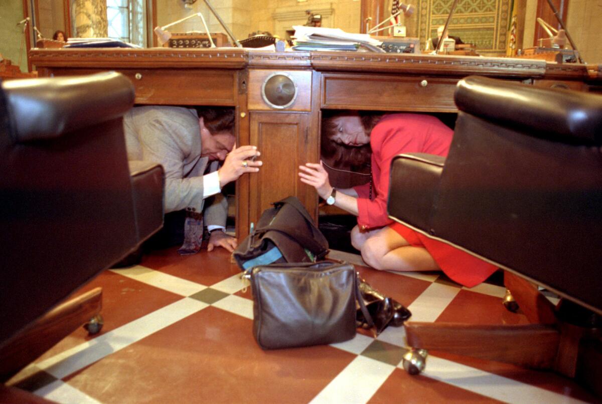 Mitglieder des Stadtrats von LA verstecken sich während einer kurzen Erdbebenvorbereitungsübung unter ihren Schreibtischen.