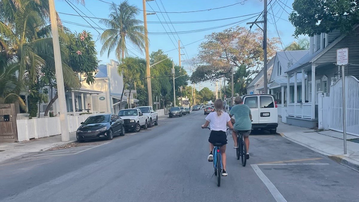 India Oxenberg fährt mit ihrem Mann draußen Fahrrad