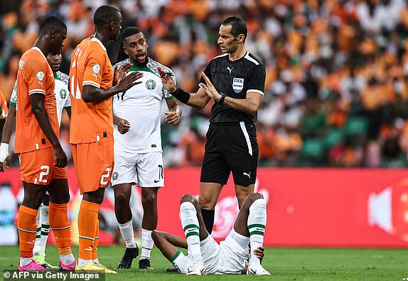 Nigeria's midfielder #17 Alex Iwobi (C) and Ivory Coast's defender #21 Evan Ndicka (2L) speak with Algerian referee Mustapha Ghorbal as Nigeria's forward #9 Victor Osimhen lies on the ground during the Africa Cup of Nations (CAN) 2024 group A football match between Ivory Coast and Nigeria at the Alassane Ouattara Olympic Stadium in Ebimpe, Abidjan, on January 18, 2024. (Photo by FRANCK FIFE / AFP) (Photo by FRANCK FIFE/AFP via Getty Images)