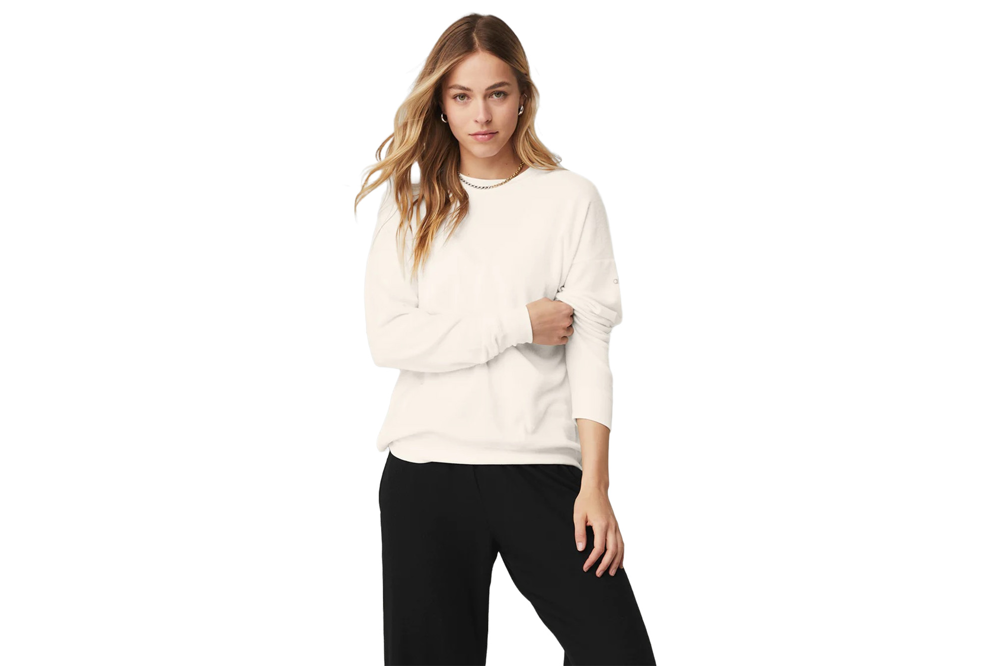 Ein Model in einem weißen Pullover und schwarzen Jogginghosen