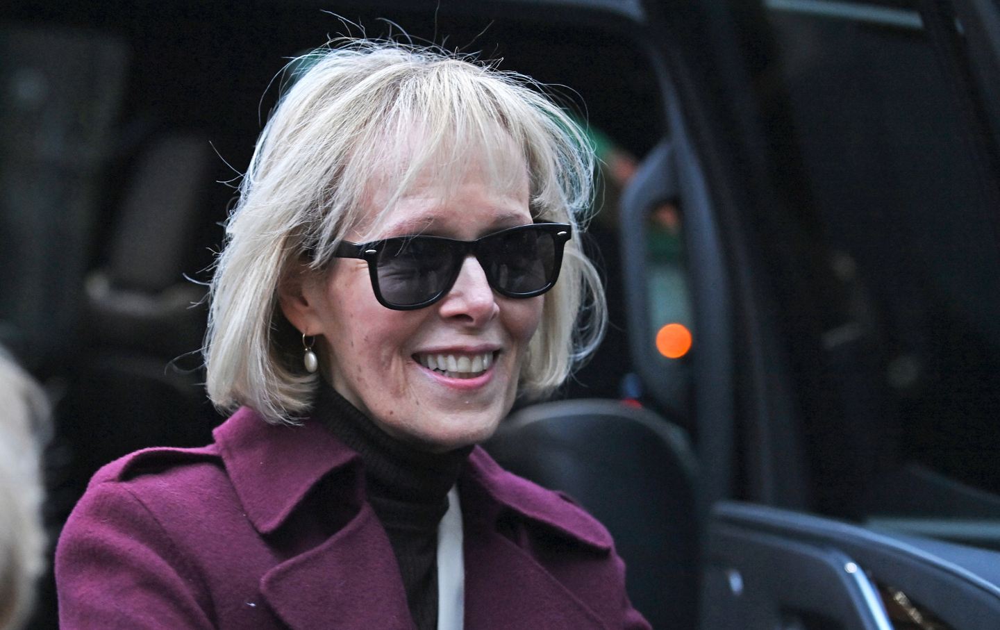 E Jean Carroll, smiling, outside a courtroom.