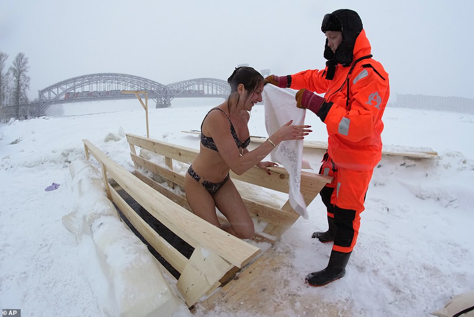 A rescue worker helps a Russian Orthodox believer after dipping in the icy water in the Neva River during a traditional Epiphany celebration in St. Petersburg on Thursday