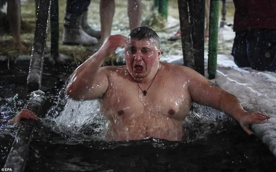 A Russian Orthodox believer takes a dip in the ice cold water of a pond during the celebrations of the Orthodox Epiphany holiday, in Moscow, Russia, on Thursday night