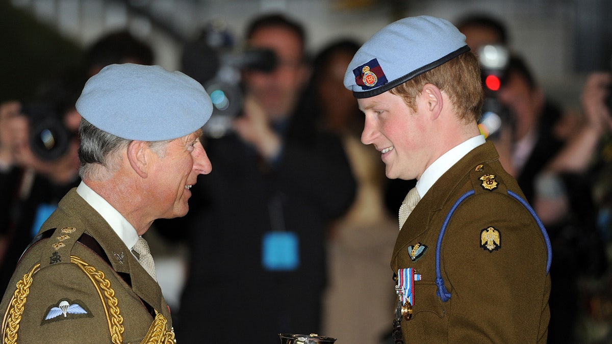 Prinz Charles lächelt Prinz Harry an, während beide Uniformen tragen
