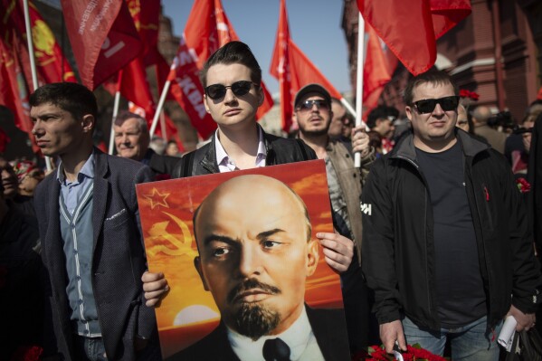 Russische Kommunisten und Unterstützer gehen mit ihren Fahnen und einem Porträt von Wladimir Lenin, dem Gründer der Sowjetunion, zu seinem Mausoleum auf dem Roten Platz in Moskau, Russland, um anlässlich seines 149. Geburtstages am Montag, den 22. April 2019, zu besuchen . (AP Photo/Alexander Zemlianichenko, Datei)