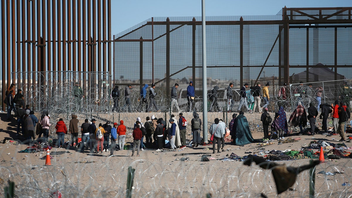 Migranten warten an der Grenzmauer
