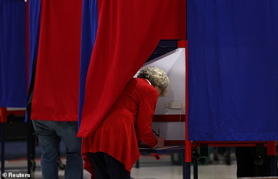 A woman fills out her ballot in a voting booth at the Webster School shortly after polls opened in the New Hampshire presidential primary election in Manchester, New Hampshire, U.S., January 23, 2024. REUTERS/Mike Segar