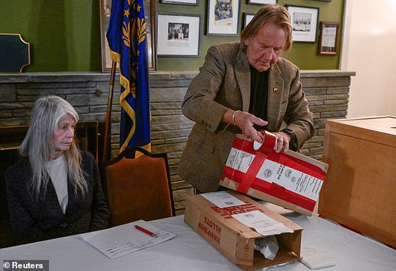 Town Moderator Tom Tillotson works next to Coralie Stepanian as people vote after midnight on the day of the U.S. presidential primary election in the living room of the Tillotson House at Balsams Hotel in Dixville Notch, New Hampshire, U.S., January 23, 2024. REUTERS/Faith Ninivaggi