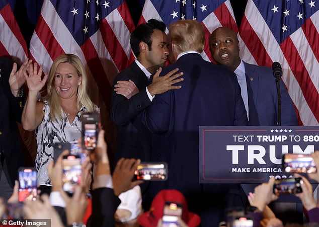 Donald Trump embraces Vivek Ramaswamy (L) and Sen. Tim Scott (right) as he leaves the stage as Rep. Marjorie Taylor Greene waves to the crowd