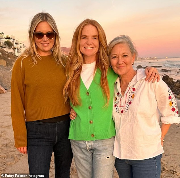 Die 51-jährige TV-Legende sah in einer auffälligen grünen Strickjacke stilvoll aus, als sie ihre Arme um zwei Freunde schlang und vor dem malerischen Meer im Sonnenuntergang posierte