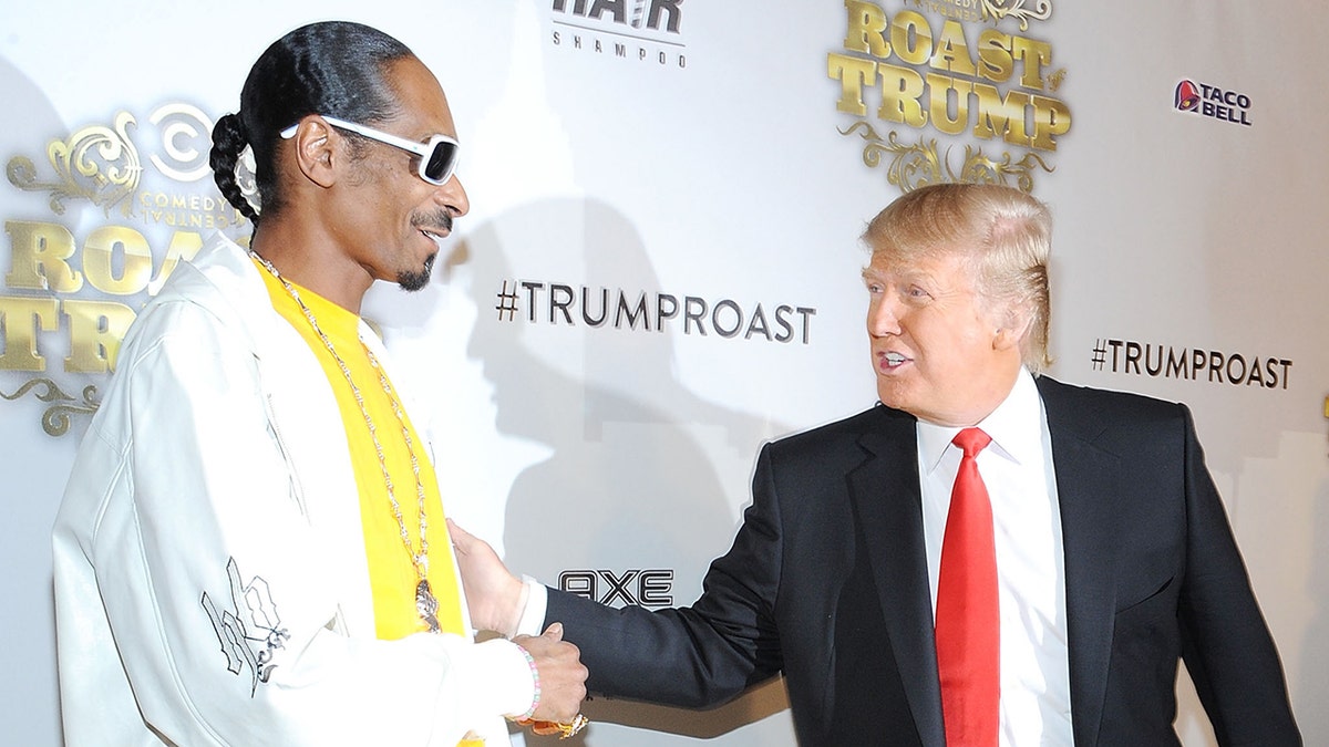 Snoop Dogg in gelbem Hemd und weißer Jacke spricht auf einem Teppich mit Donald Trump