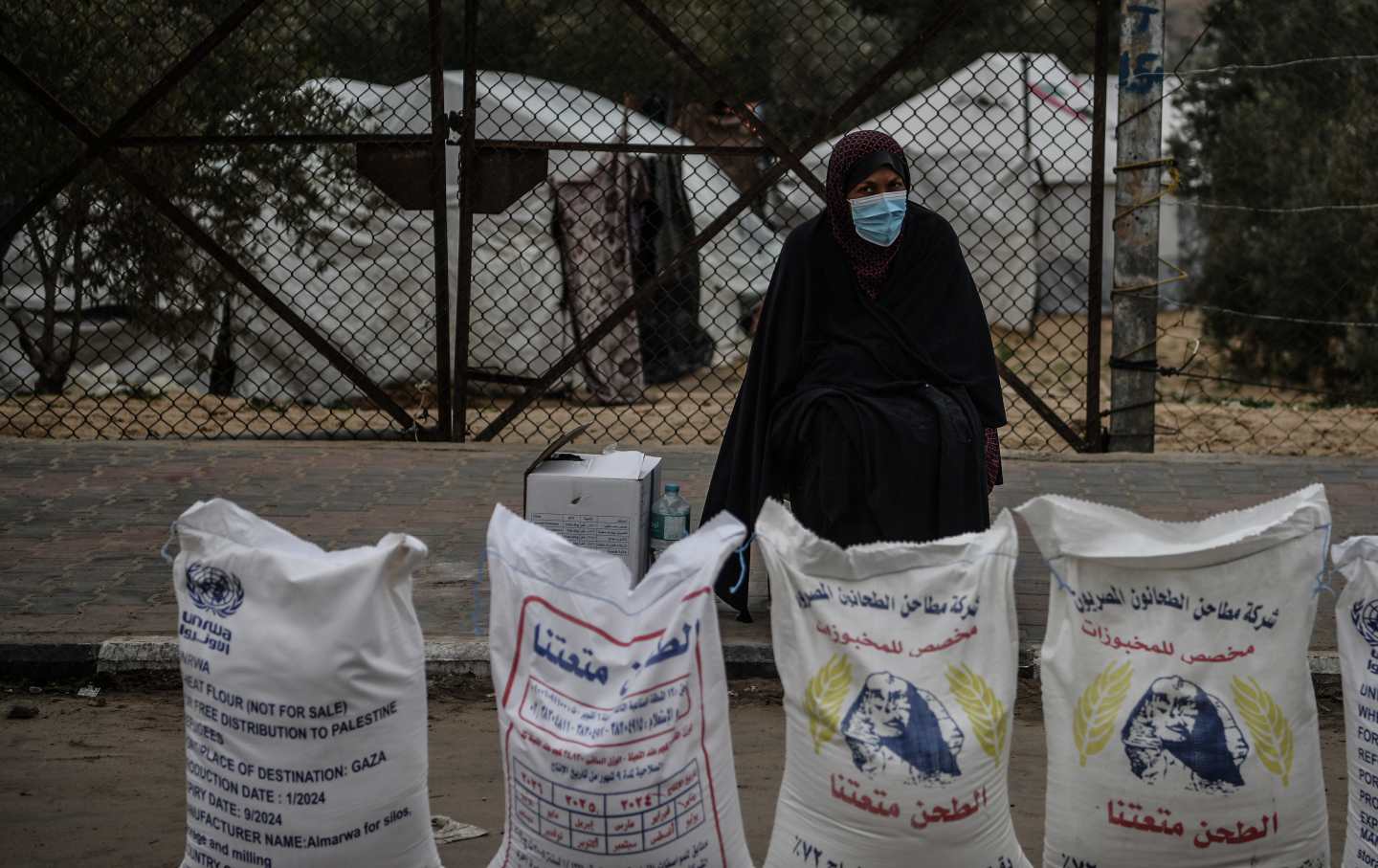 Eine Palästinenserin steht in einer Flüchtlingssiedlung in der Stadt Rafah im Gazastreifen neben Mehlsäcken, die vom Hilfswerk der Vereinten Nationen für Palästinenserhilfe verteilt wurden.