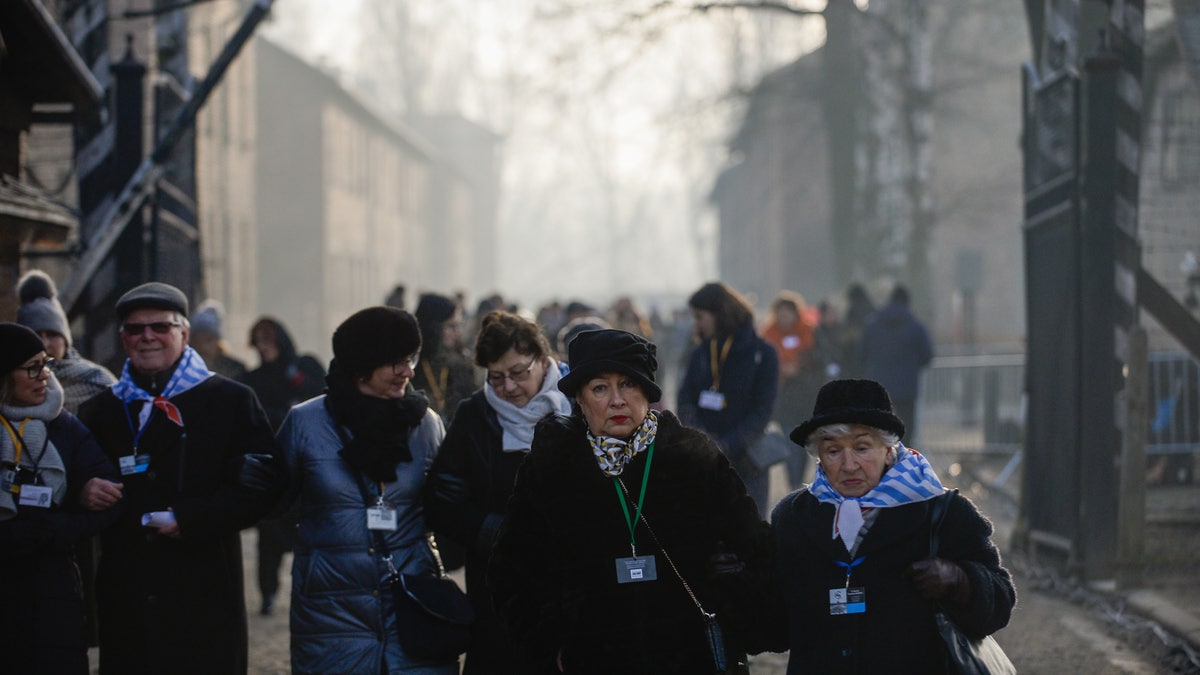 Überlebende des Konzentrationslagers Auschwitz gehen am Haupttor vorbei