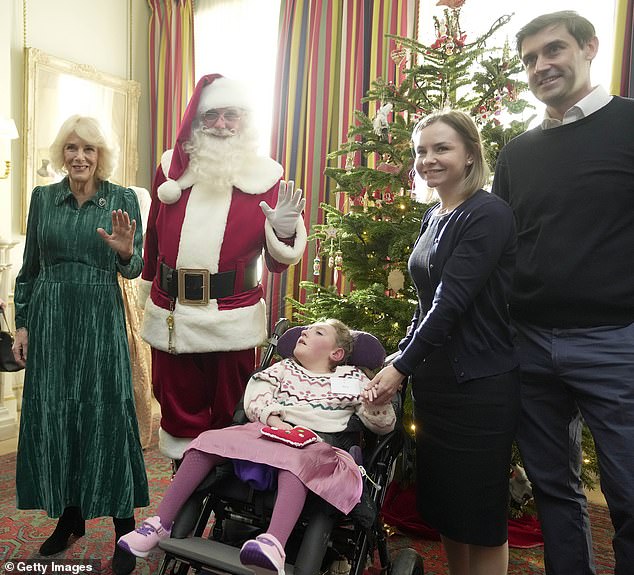 Britain's Queen Camilla poses with a man dressed as Father Christmas as she invited children, supported by Helen & Douglas House and Roald Dahl's Marvellous Children's Charity, to decorate the Christmas tree and receive a few festive surprises at Clarence House