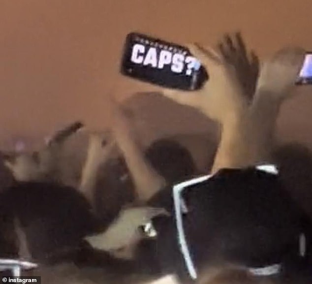 In den sozialen Medien veröffentlichtes Videomaterial vom Festival zeigte eine Person, die ein Mobiltelefon mit der Aufschrift „Caps?“ hochhielt.  auf dem Bildschirm geschrieben (im Bild)