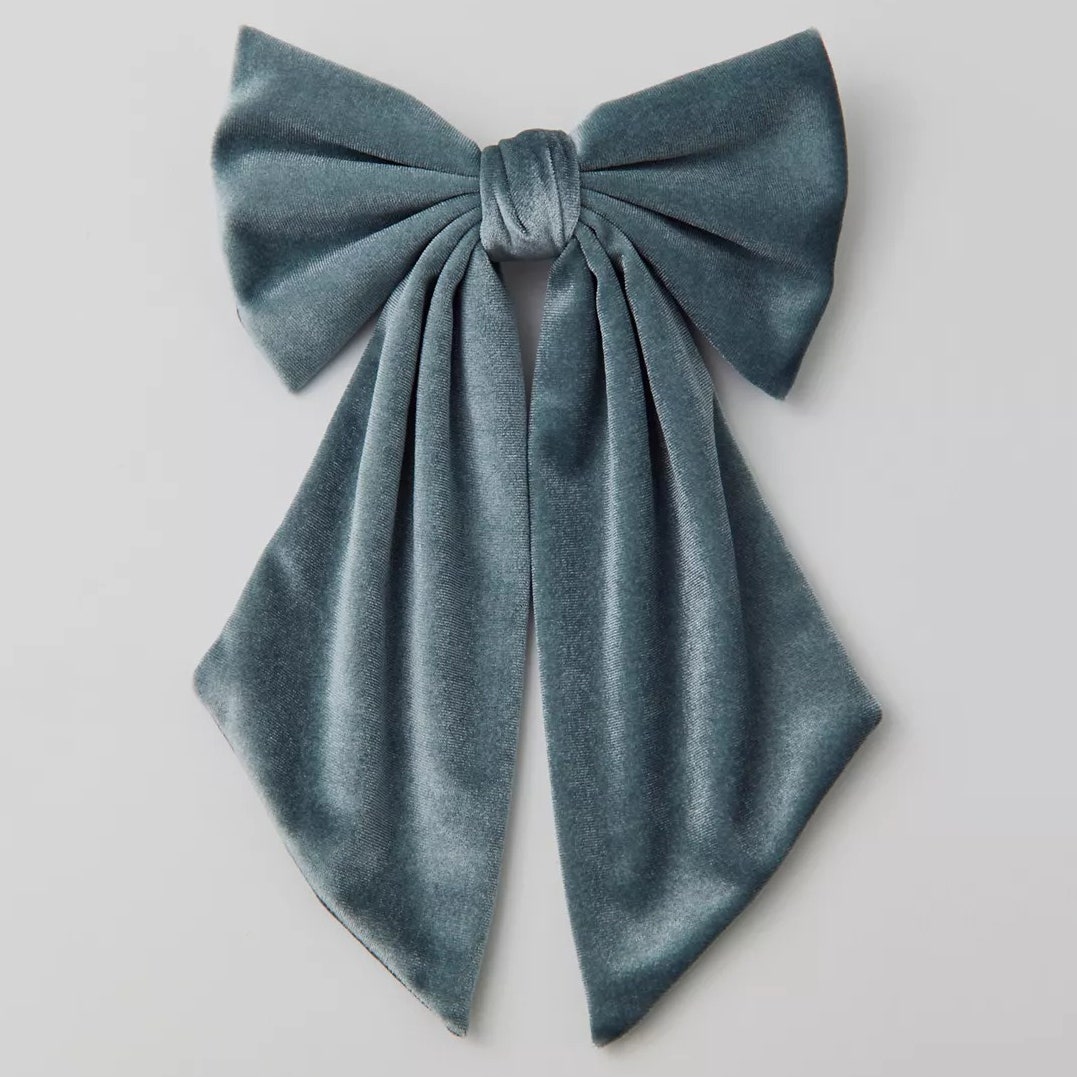 Haarspange aus Samt von Urban Outfitters. Blaue Haarspange aus Samt mit Schleife auf grauem Hintergrund