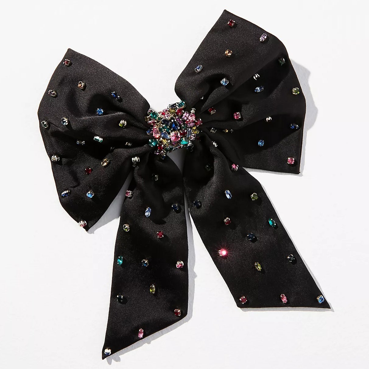 Mignonne Gavigan Grace Crystal Hair Bow Haarspange mit schwarzer Schleife und mehrfarbigen Edelsteinen darauf auf cremefarbenem Hintergrund