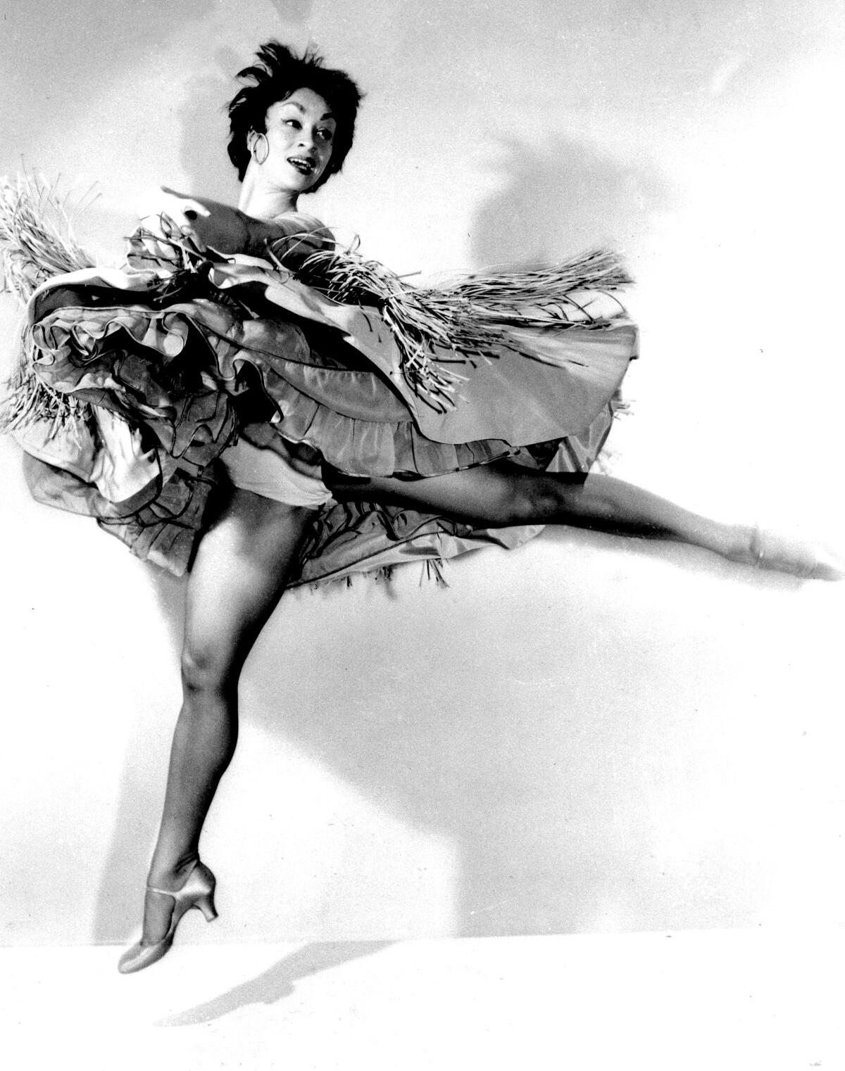 Ein Schwarz-Weiß-Foto zeigt die Performerin Chita Rivera mitten im Sprung, ihre Röcke flattern um sie herum.