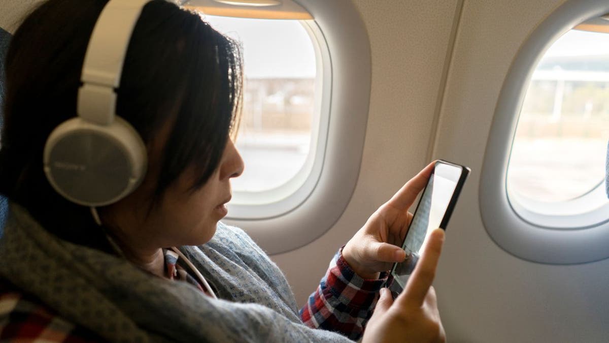 Eine Frau telefoniert an Bord eines Flugzeugs.